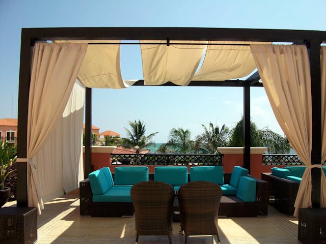 A covered patio with blue cushioned furniture.