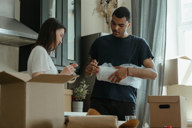 two people unpacking moving boxes in a kitchen