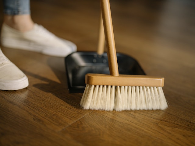 person sweeping a brown wooden floor