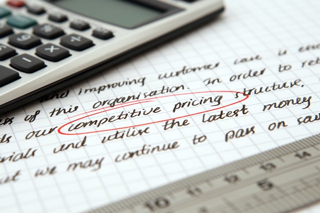 calculator on paper with writing on it and "competitive pricing" circled in red pen