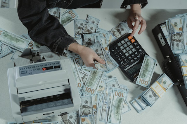table filled with money and person using calculator