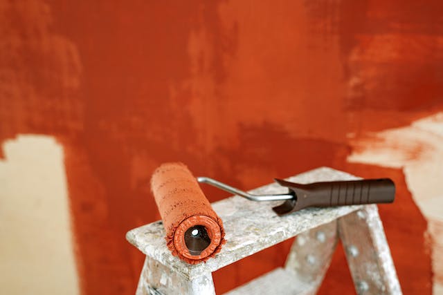 A roller sitting in front of a patchy orange wall.