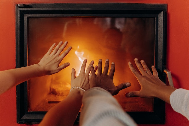 people holding their hands over a fireplace